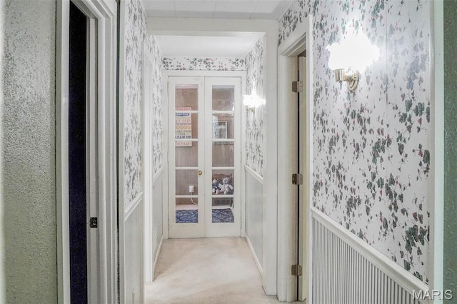 hallway with wallpapered walls, french doors, and carpet floors