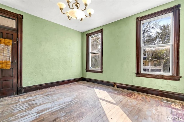 1041 Garth Ave, Saint Louis, MO 63147 - unfurnished room featuring a chandelier, hardwood / wood-style floors, plenty of natural light, a textured wall, and baseboards