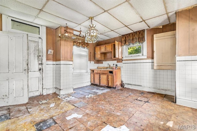 1041 Garth Ave, Saint Louis, MO 63147 - kitchen with a drop ceiling, a sink, a chandelier, brown cabinets, and wooden walls