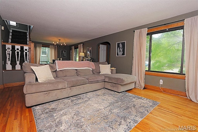 2754 Adeline Ave, Cape Girardeau, MO 63701 - living room featuring a chandelier, arched walkways, wood finished floors, healthy amount of natural light, and a textured ceiling