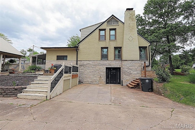 2754 Adeline Ave, Cape Girardeau, MO 63701 - view of front of home with stairway, stone siding, a chimney, and a sunroom
