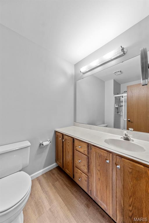 324 Trailview Ave, Saint Peters, MO 63376 - full bath with toilet, wood finished floors, vanity, a shower with shower door, and baseboards