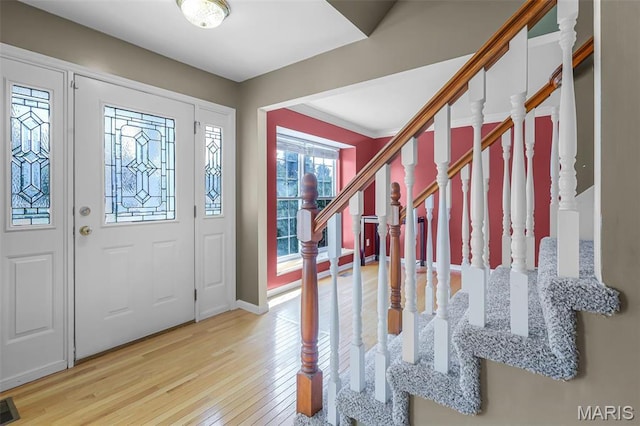 entryway with light wood-type flooring, stairway, and baseboards
