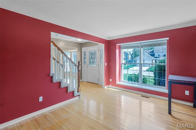 foyer entrance featuring baseboards, stairway, wood finished floors, and ornamental molding