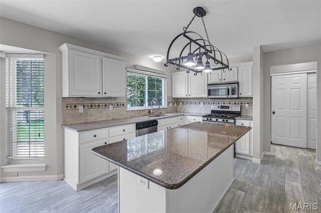 kitchen with stainless steel appliances, a sink, white cabinetry, and light wood-style flooring