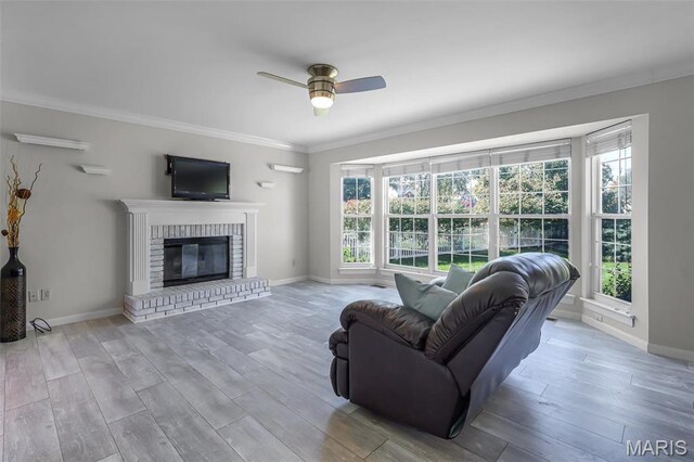 living area with healthy amount of natural light, a ceiling fan, crown molding, and wood finished floors