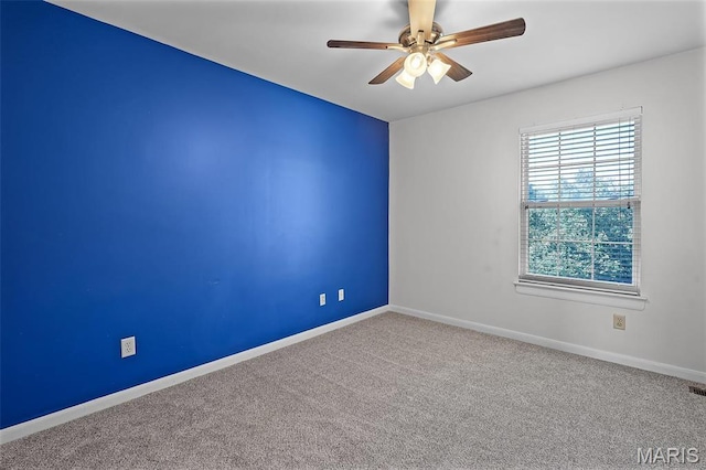 carpeted spare room with ceiling fan and baseboards