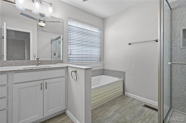 full bath with a shower stall, vanity, a bath, and wood finished floors