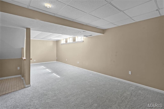 basement with carpet flooring, a paneled ceiling, and baseboards