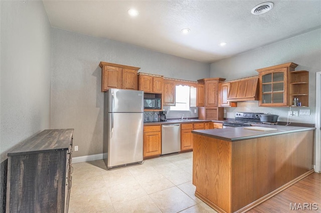 kitchen with appliances with stainless steel finishes, glass insert cabinets, premium range hood, dark countertops, and a peninsula