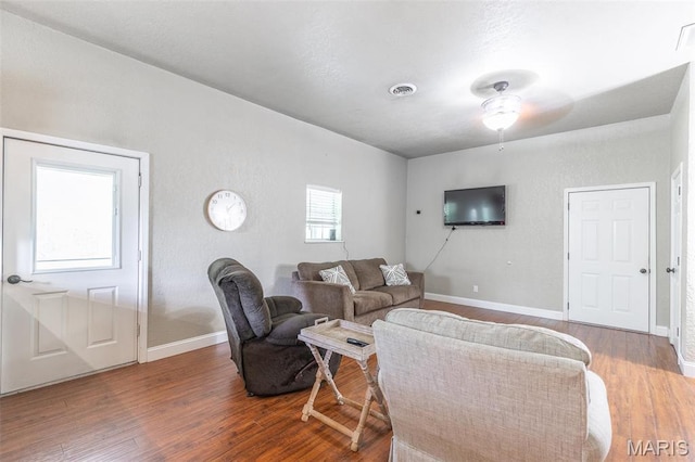 living room featuring wood finished floors, baseboards, and ceiling fan
