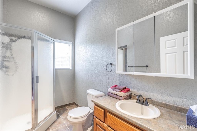 bathroom featuring a textured wall, a stall shower, vanity, tile patterned floors, and toilet