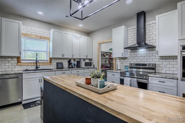 22950 Pin Oak Dr, Lebanon, MO 65536 - kitchen featuring butcher block counters, stainless steel appliances, wall chimney exhaust hood, a sink, and tasteful backsplash