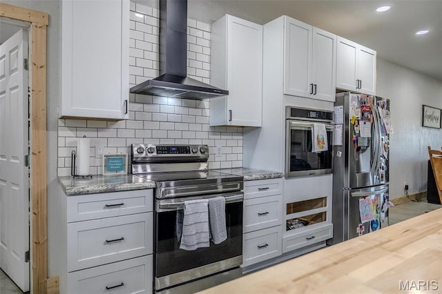 22950 Pin Oak Dr, Lebanon, MO 65536 - kitchen with appliances with stainless steel finishes, wall chimney range hood, decorative backsplash, recessed lighting, and white cabinetry