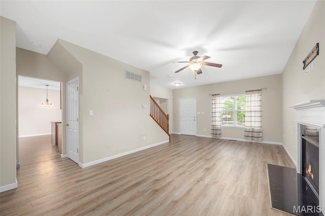554 Springhurst Pkwy, Ofallon, MO 63368 - unfurnished living room with a fireplace with flush hearth, light wood finished floors, stairs, and a chandelier