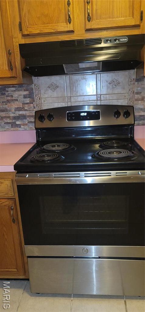 10506 Camden Park Dr, Saint Louis, MO 63135 - kitchen featuring stainless steel electric stove, under cabinet range hood, backsplash, and light tile patterned floors