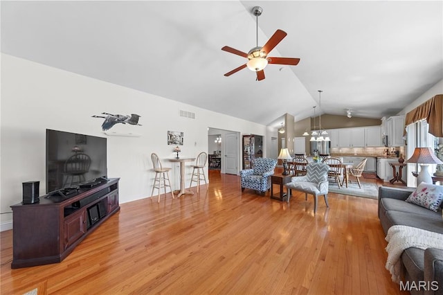 living room featuring ceiling fan, vaulted ceiling, and light wood-type flooring
