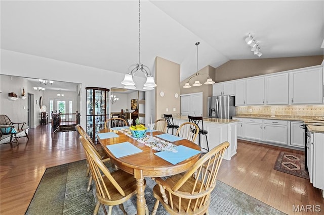 dining room with vaulted ceiling, hardwood / wood-style flooring, and a chandelier