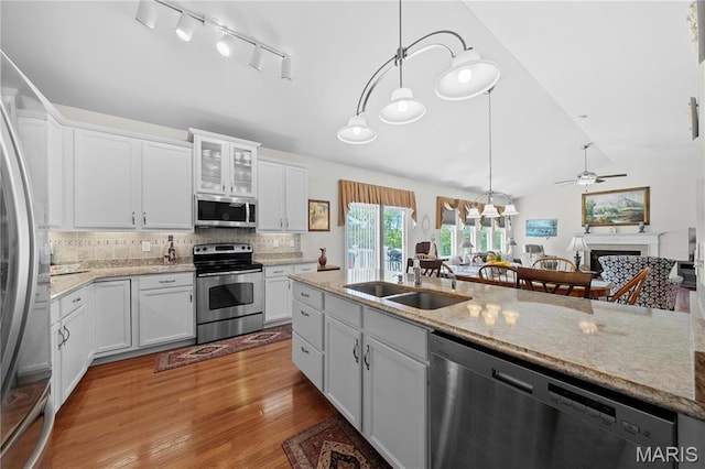 kitchen with stainless steel appliances, a sink, lofted ceiling, wood finished floors, and white cabinetry