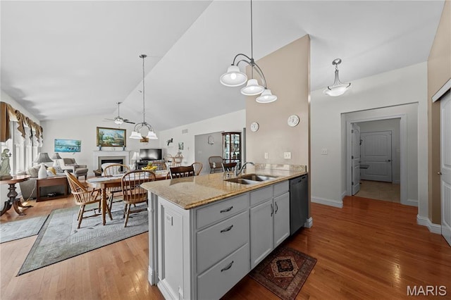 kitchen with dishwasher, a ceiling fan, lofted ceiling, a sink, and a fireplace