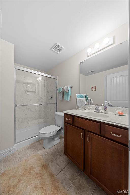 bathroom featuring a shower stall, vanity, toilet, and tile patterned flooring