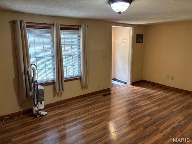 empty room featuring dark wood-style floors, baseboards, and a textured ceiling