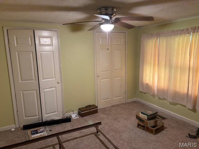 unfurnished living room with ceiling fan, carpet, and baseboards