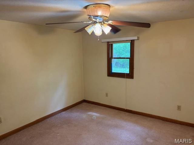 empty room featuring ceiling fan, light colored carpet, and baseboards