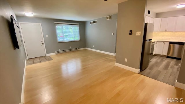 unfurnished living room with a baseboard heating unit, light wood-type flooring, and baseboards