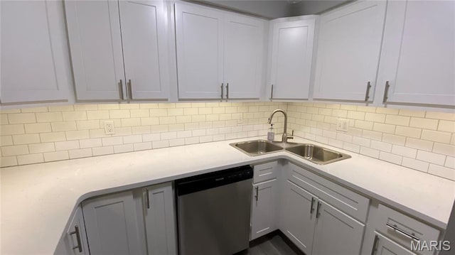 kitchen featuring stainless steel dishwasher, a sink, light countertops, and decorative backsplash