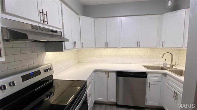 kitchen with stainless steel appliances, under cabinet range hood, a sink, light countertops, and white cabinetry