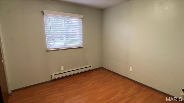 empty room featuring a baseboard heating unit, light wood finished floors, and baseboards