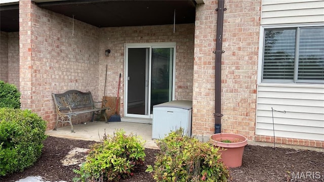 view of exterior entry with a patio area and brick siding
