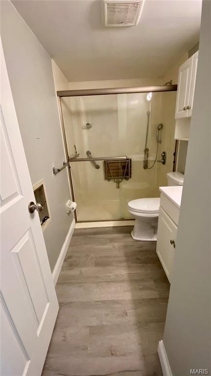 bathroom with a stall shower, wood finished floors, toilet, baseboards, and vanity
