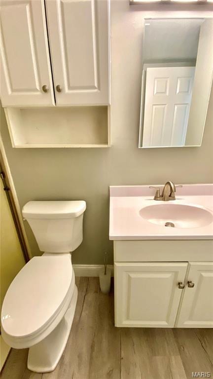 bathroom featuring wood finished floors, toilet, vanity, and baseboards