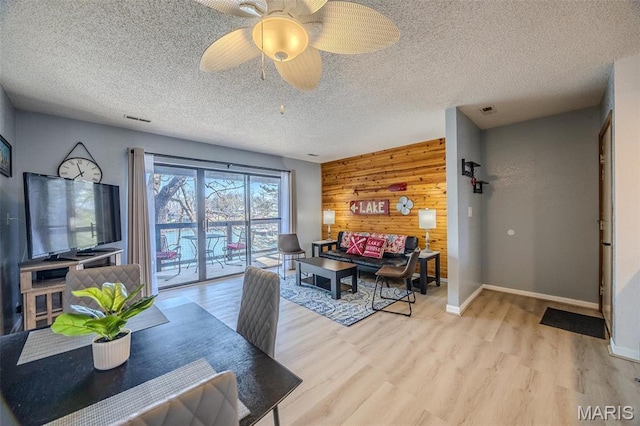 256 Lone Oak Unit 15, Sunrise Beach, MO 65079 - living room featuring wooden walls, wood finished floors, baseboards, a textured ceiling, and a ceiling fan