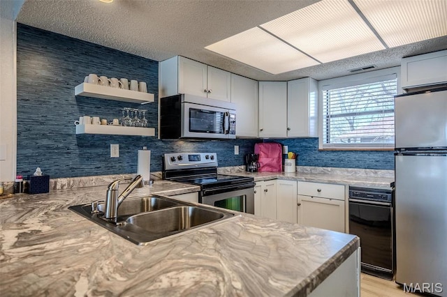 256 Lone Oak Unit 15, Sunrise Beach, MO 65079 - kitchen with stainless steel appliances, a sink, white cabinetry, light countertops, and a textured ceiling