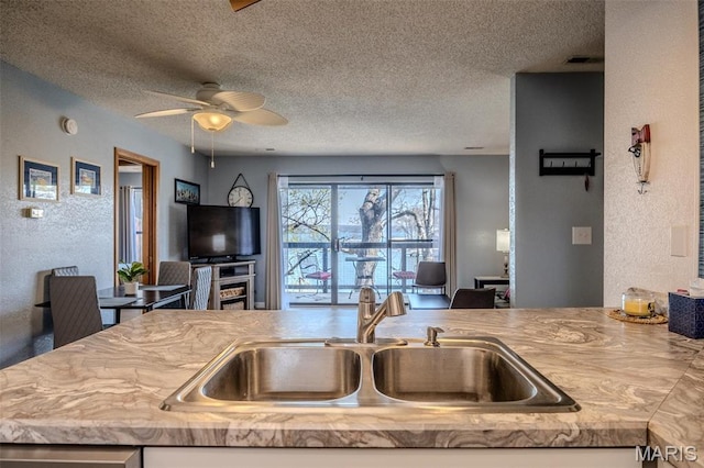 256 Lone Oak Unit 15, Sunrise Beach, MO 65079 - kitchen featuring a sink, a textured ceiling, open floor plan, a ceiling fan, and a textured wall