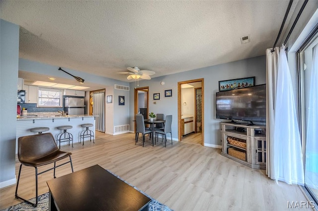 256 Lone Oak Unit 15, Sunrise Beach, MO 65079 - living area featuring a textured ceiling, light wood-type flooring, baseboards, and a ceiling fan