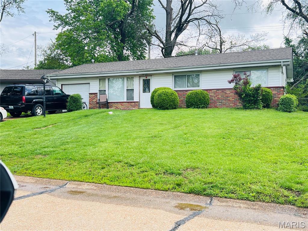 ranch-style house with brick siding, a garage, and a front yard
