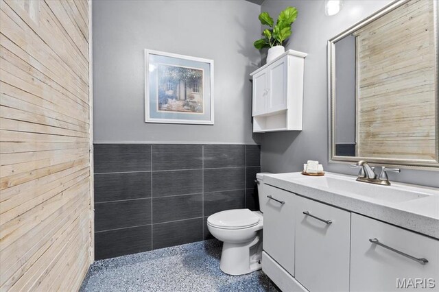 2226 Bay Tree Dr, Saint Peters, MO 63376 - bathroom with speckle patterned floor, wood walls, toilet, and vanity