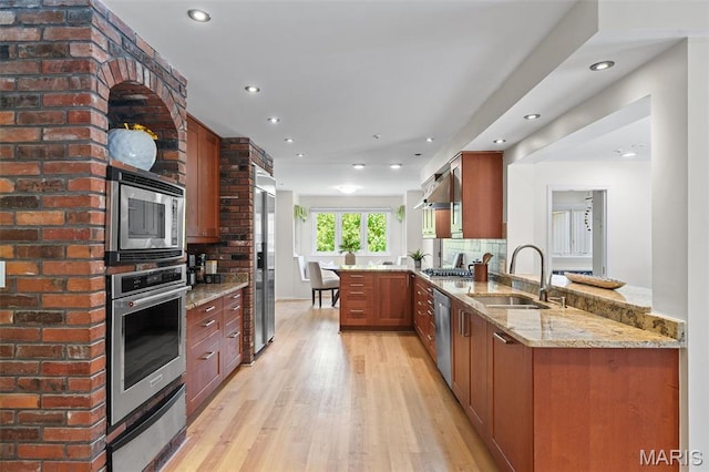 2125 Crystal Dr, Saint Louis, MO 63131 - kitchen featuring appliances with stainless steel finishes, a sink, a peninsula, light wood-style flooring, and light stone counters