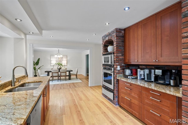 2125 Crystal Dr, Saint Louis, MO 63131 - kitchen with appliances with stainless steel finishes, a sink, light wood-style flooring, recessed lighting, and light stone counters