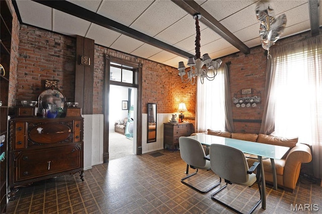 dining space featuring brick wall, a chandelier, tile patterned floors, and beam ceiling