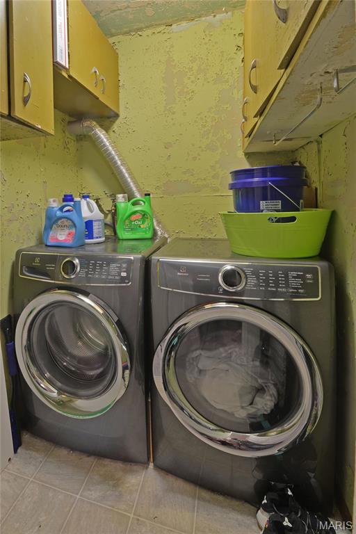 laundry room featuring cabinet space, washing machine and dryer, and tile patterned flooring
