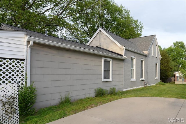 view of home's exterior with a yard, a patio area, and a shingled roof