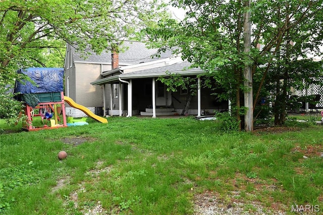 view of green lawn with a playground and entry steps