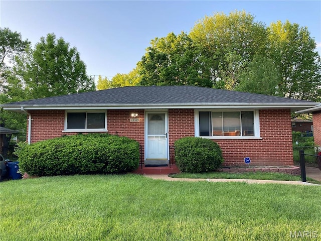 view of front facade with a front lawn, brick siding, and roof with shingles