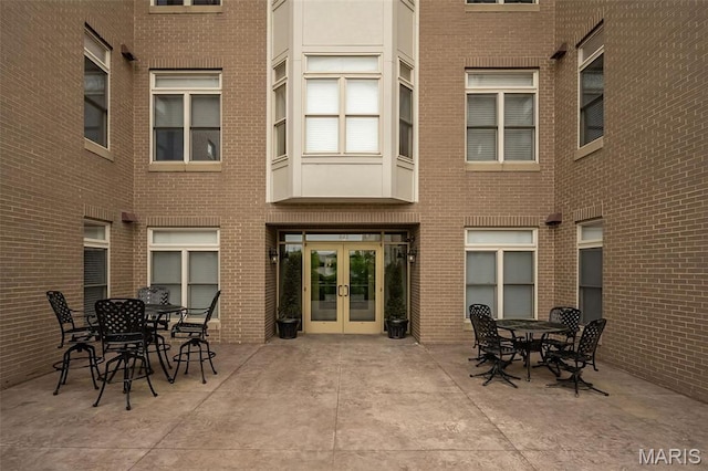 back of property with french doors, brick siding, a patio area, and outdoor dining space