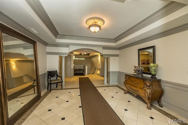 hallway featuring decorative columns, arched walkways, light tile patterned floors, inlaid floor details, and ornamental molding